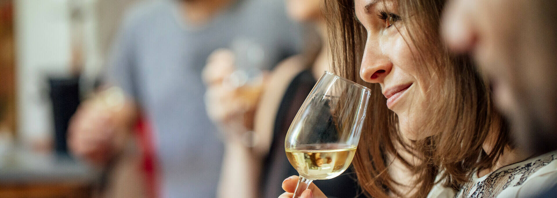 Plan rapproché d'une dégustation de vin blanc, femme portant le verre à son nez