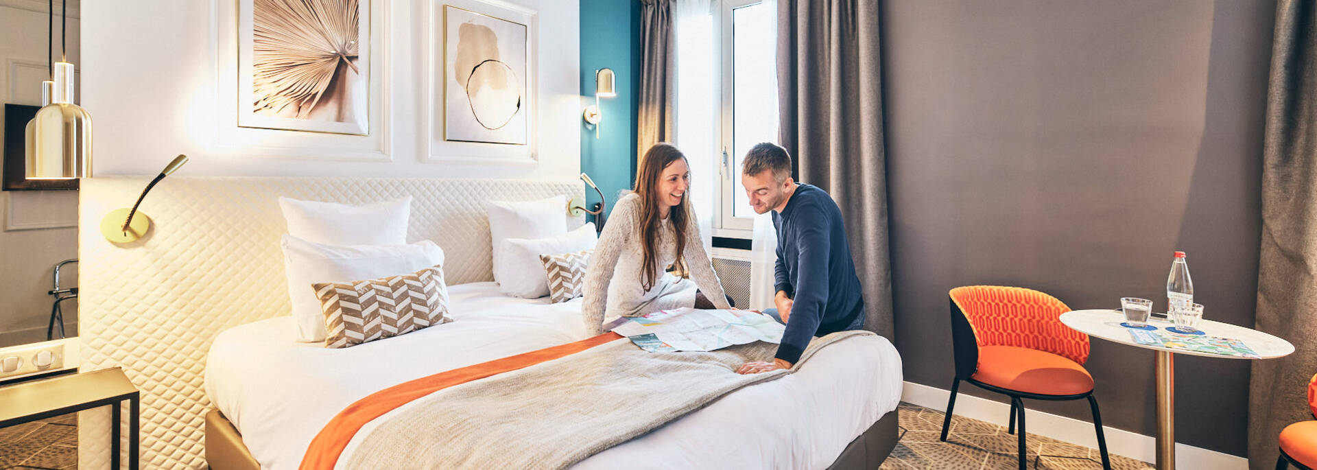 Couple talking in front of a map, sitting on the bed in a hotel room