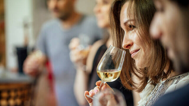 Plan rapproché d'une dégustation de vin blanc, femme portant le verre à son nez