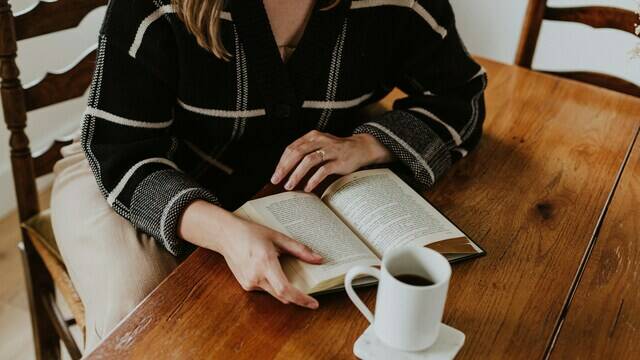 Femme qui lit un livre dans un café