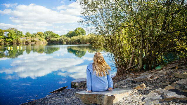 Woman sitting at the edge of a lake in Les Ardoisières