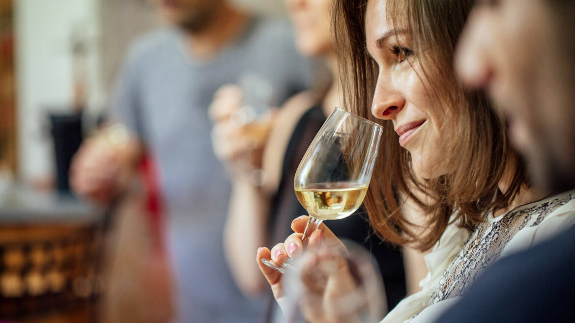 Plan rapproché d'une dégustation de vin blanc, femme portant le verre à son nez