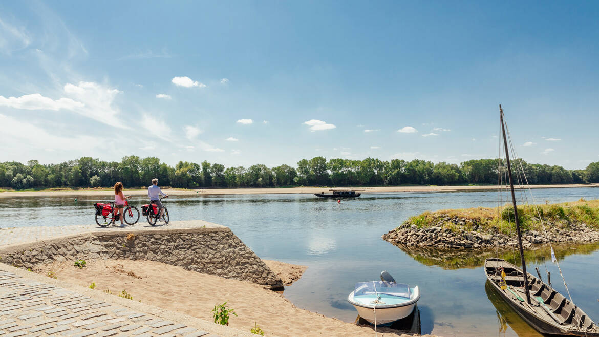 Couple à vélo arrêté au bord du fleuve pour regarder une gabarre passer