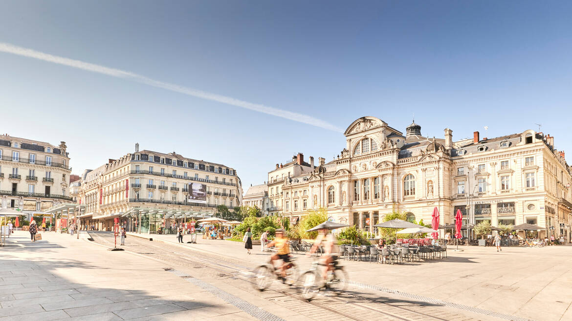 Deux cyclistes passant place du Ralliement devant le Grand Théâtre