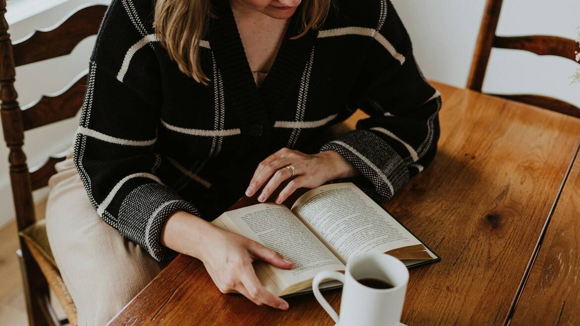 Femme qui lit un livre dans un café