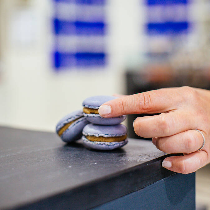 Plan rapproché d'une main qui prend un macaron couleur bleu ardoise